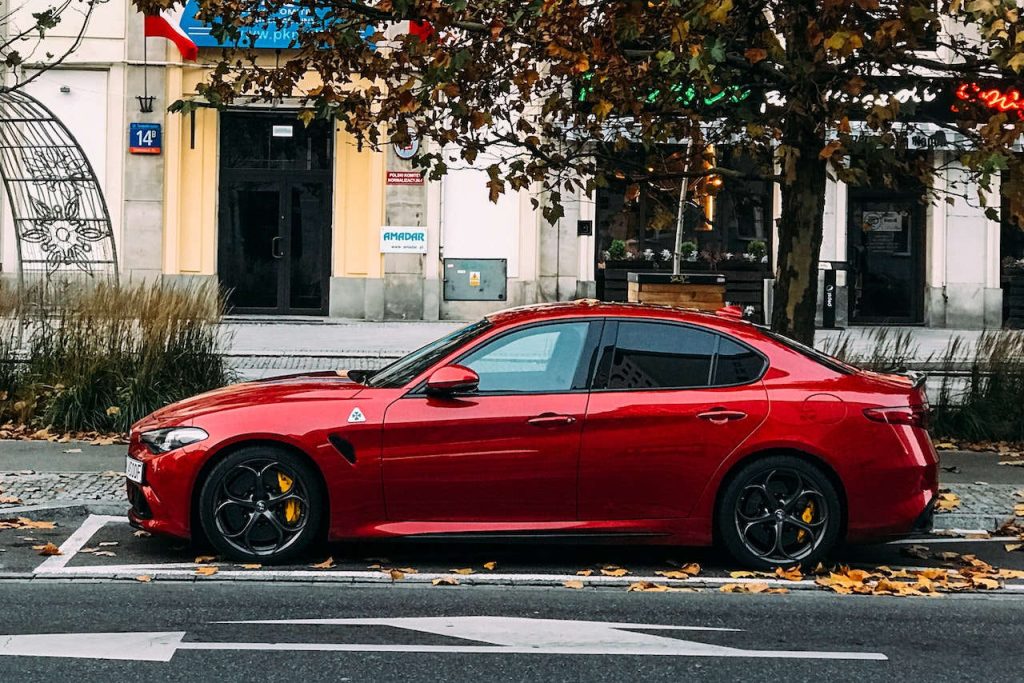Czerwony samochód zakupiony w formie leasingu stoi na parkingu wzdłuż ulicy